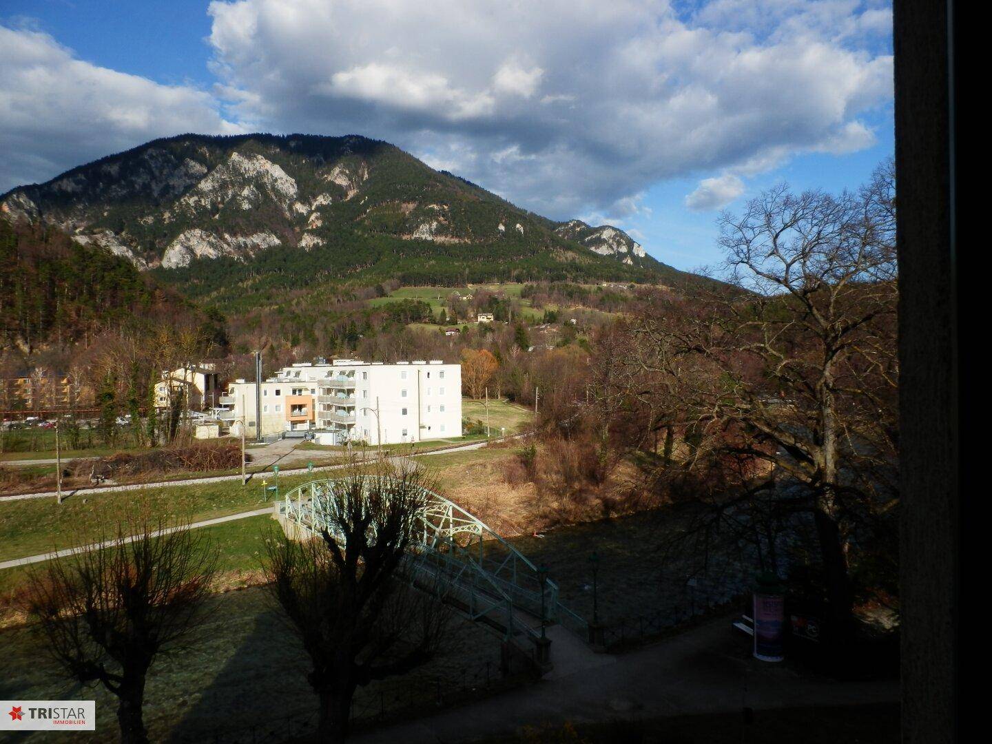 Panoramablick auf die umliegende Berglandschaft, einen Fluss und ein Wohngebäude.