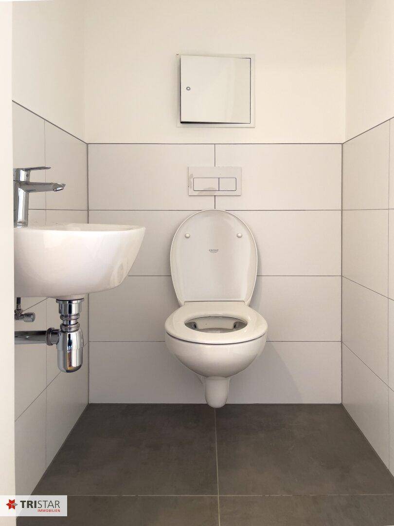 Modernes Gäste-WC mit wandhängender Toilette und kleinem Waschbecken.