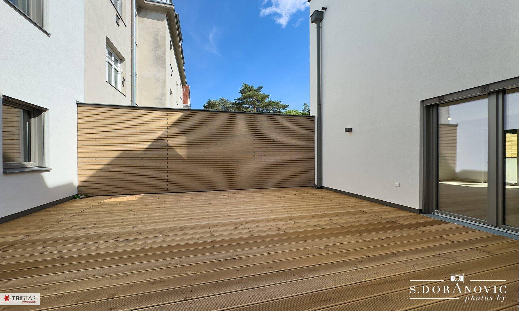 Geräumige Holzterrasse mit Sichtschutz, perfekt für Privatsphäre und Entspannung im Freien.