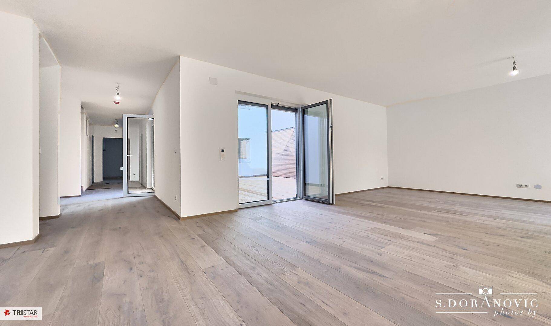 Heller, offener Wohnbereich mit modernem Holzboden und großen Glastüren zur Terrasse.