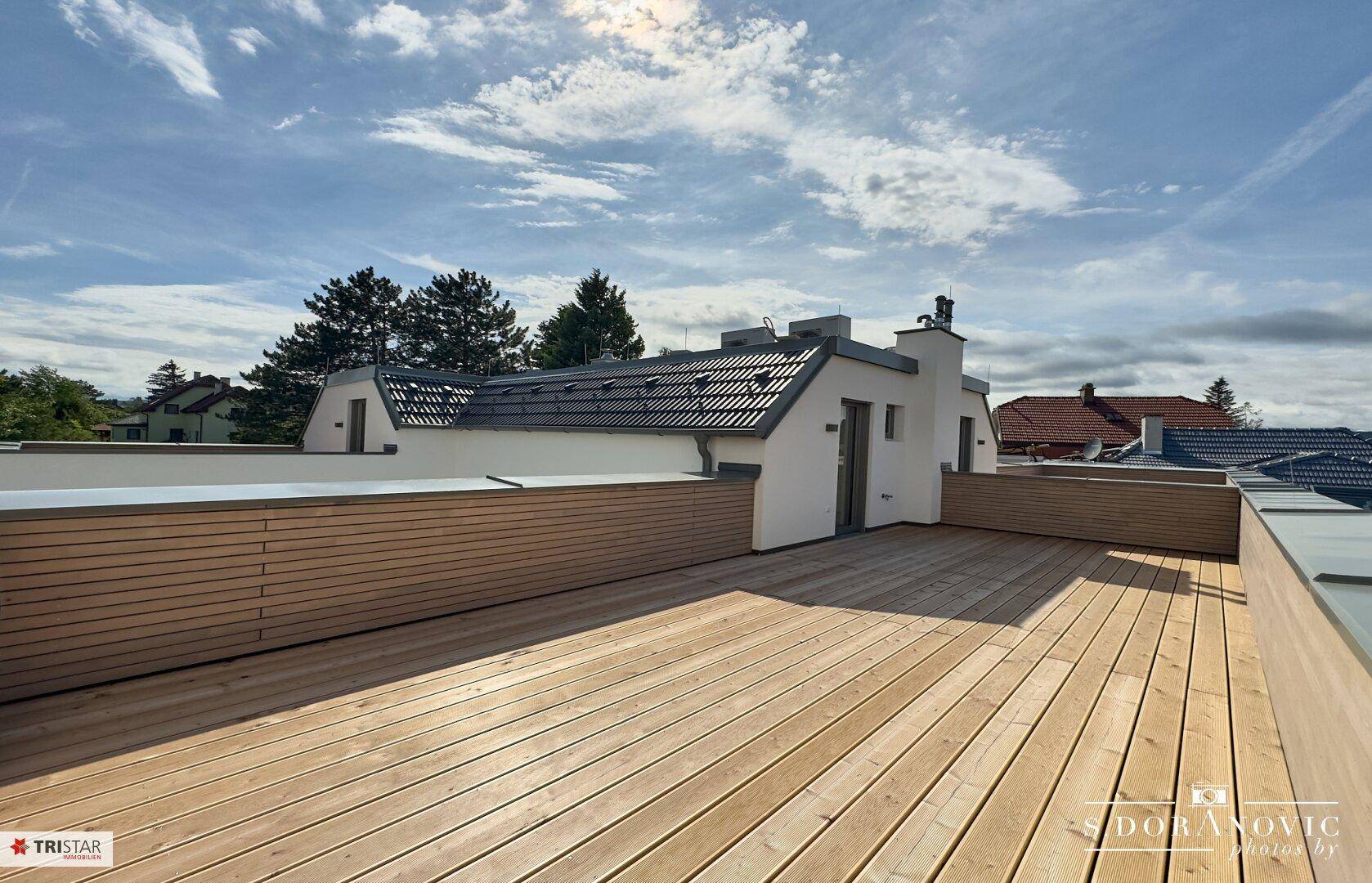 Großzügige Dachterrasse mit Holzboden und umlaufender Holzverkleidung, ideal zum Entspannen.