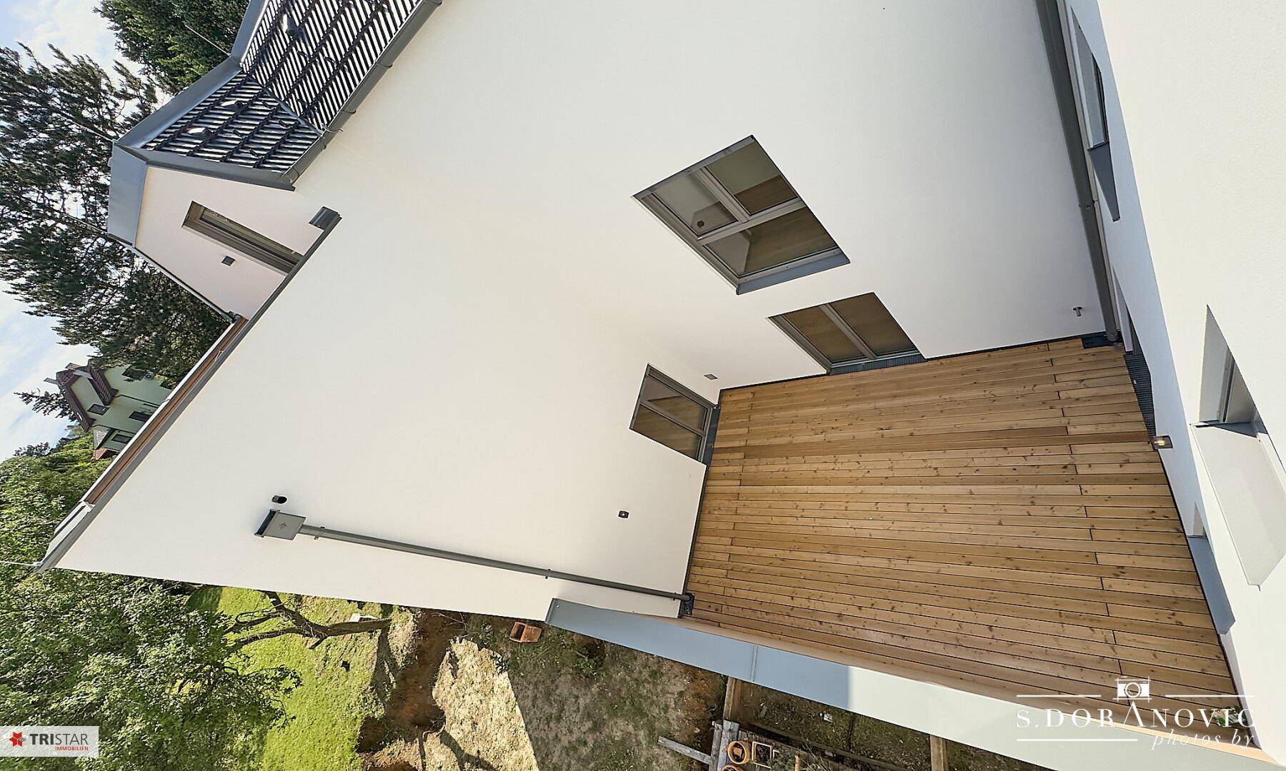 Große Holzterrasse mit viel Sonnenlicht, ideal für Outdoor-Aktivitäten und Entspannung.