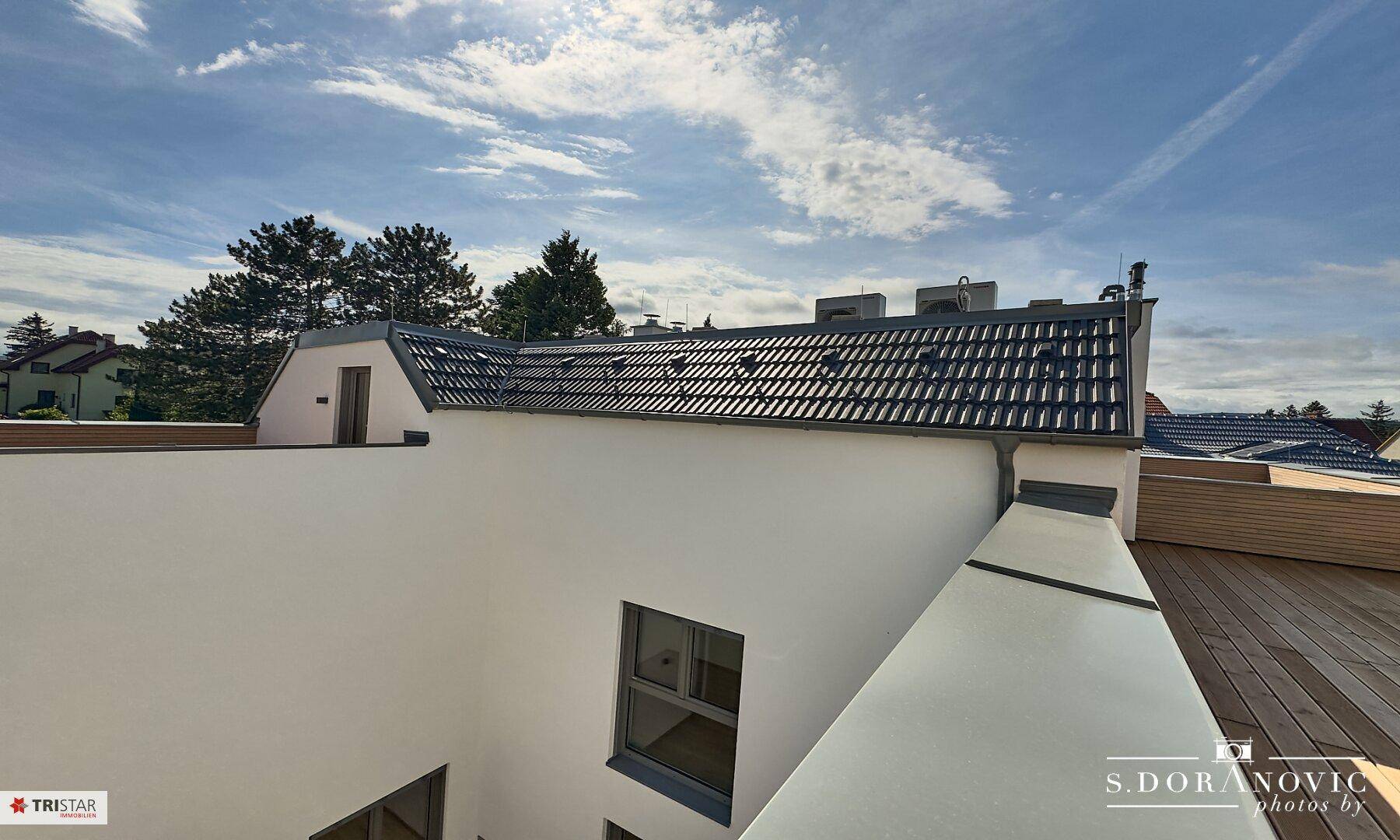 Blick von der Dachterrasse auf das Ziegeldach und die umliegende Wohnbebauung.