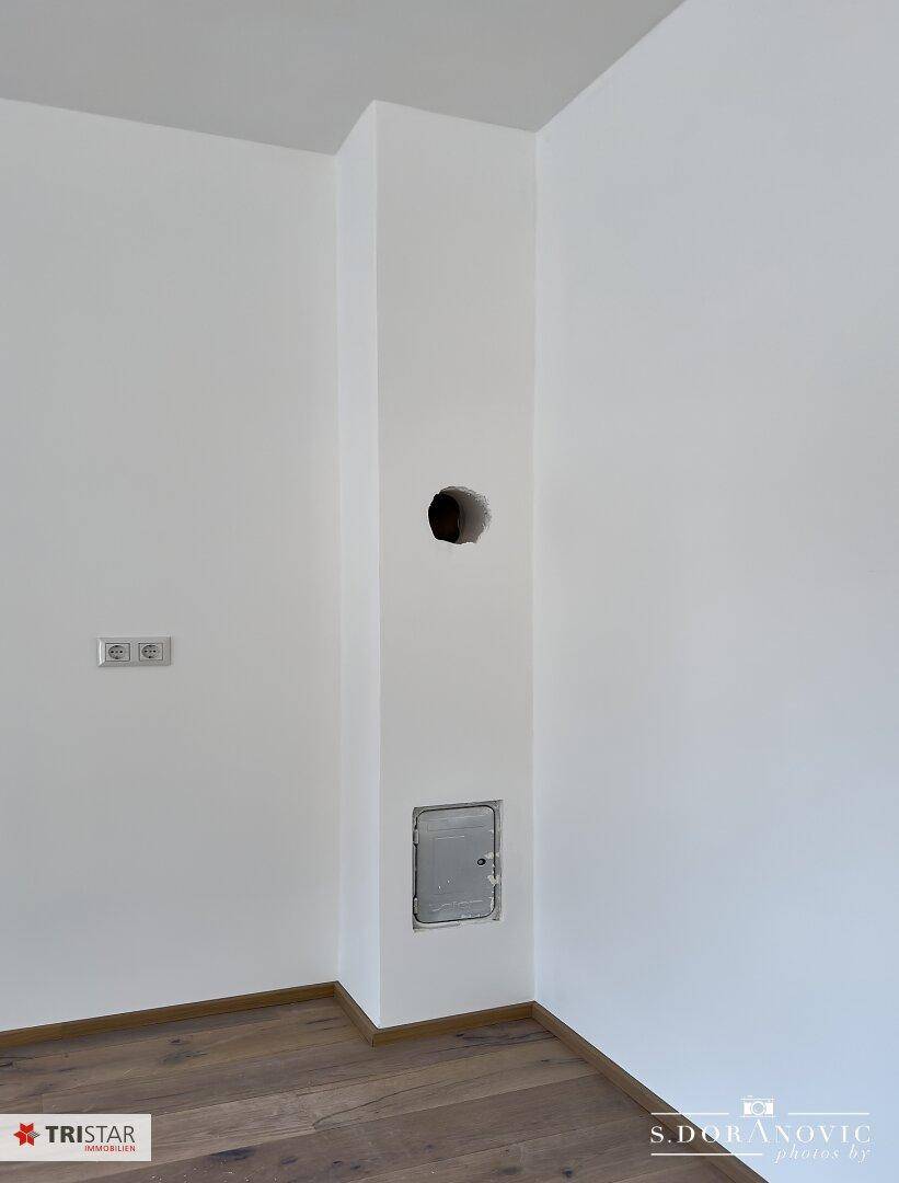 Weiße Wand mit Steckdosen und einer vorbereiteten Öffnung für Installationen.