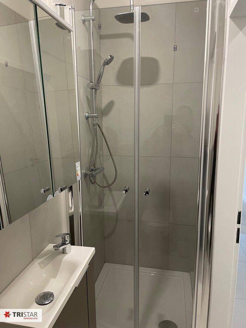 Funktionales Badezimmer mit Duschkabine, Waschbecken und praktischem Spiegelschrank.