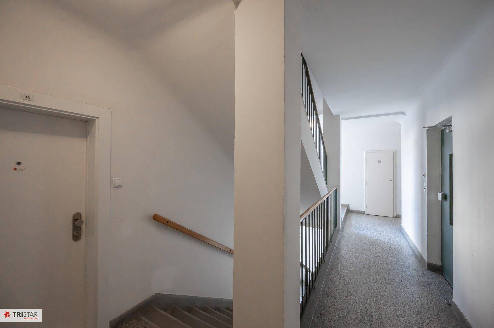 Geräumiger Treppenbereich und Flur mit Zugang zu den Wohnungen und einem Geländer.