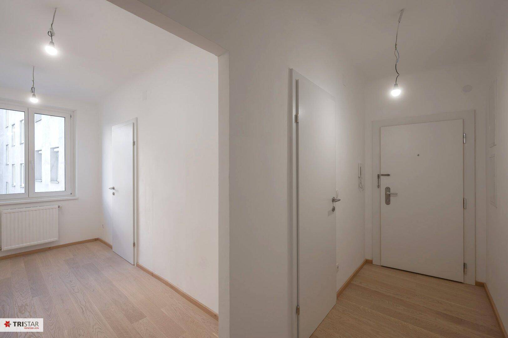 Heller Eingangsbereich mit Parkettboden und Zugang zu weiteren Zimmern der Wohnung.