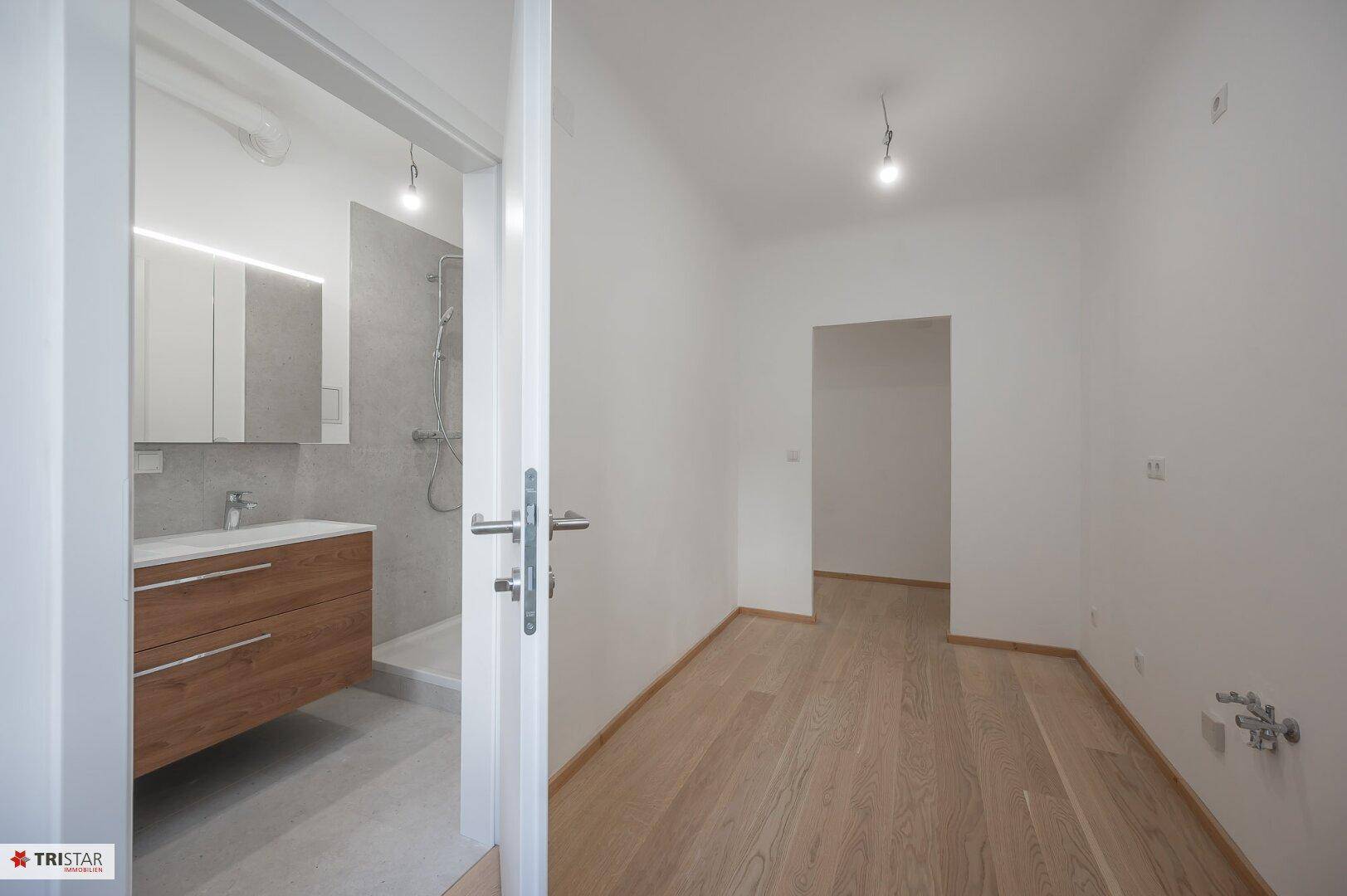 Heller Raum mit Parkettboden und direktem Zugang zu einem modernen Badezimmer.
