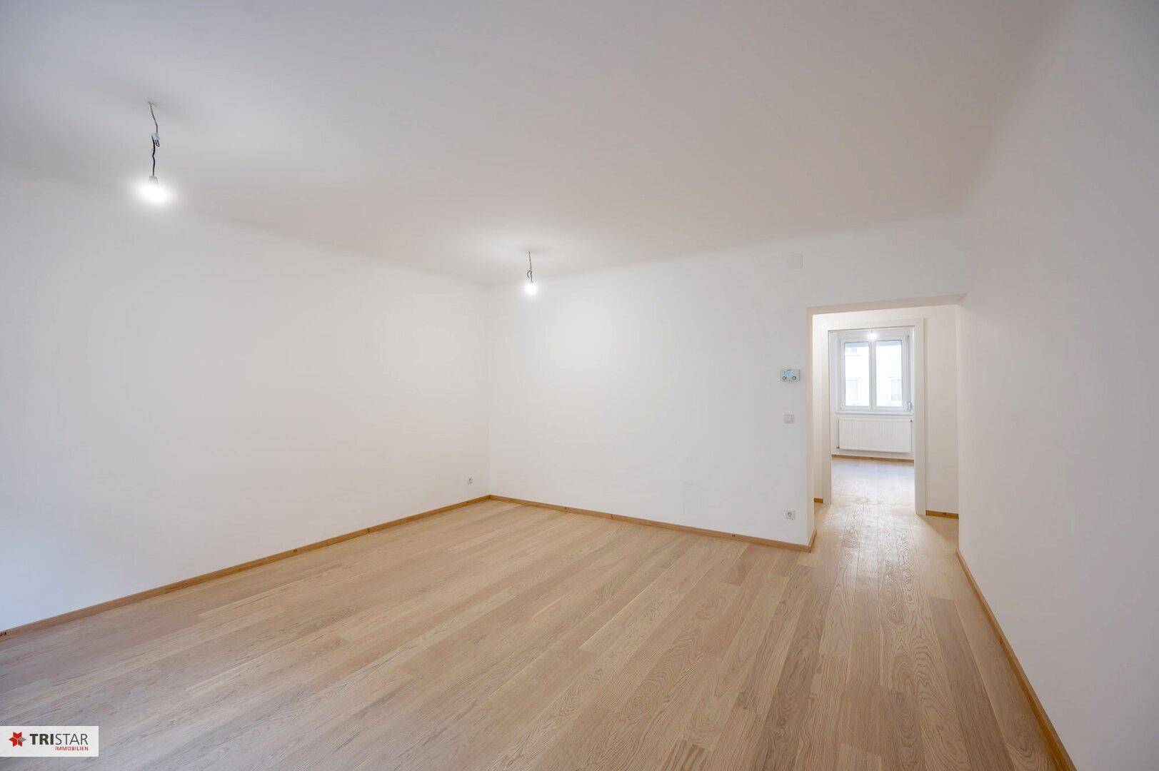 Geräumiger, heller Raum mit Parkettboden und weiß gestrichenen Wänden, ideal für Wohnzwecke.