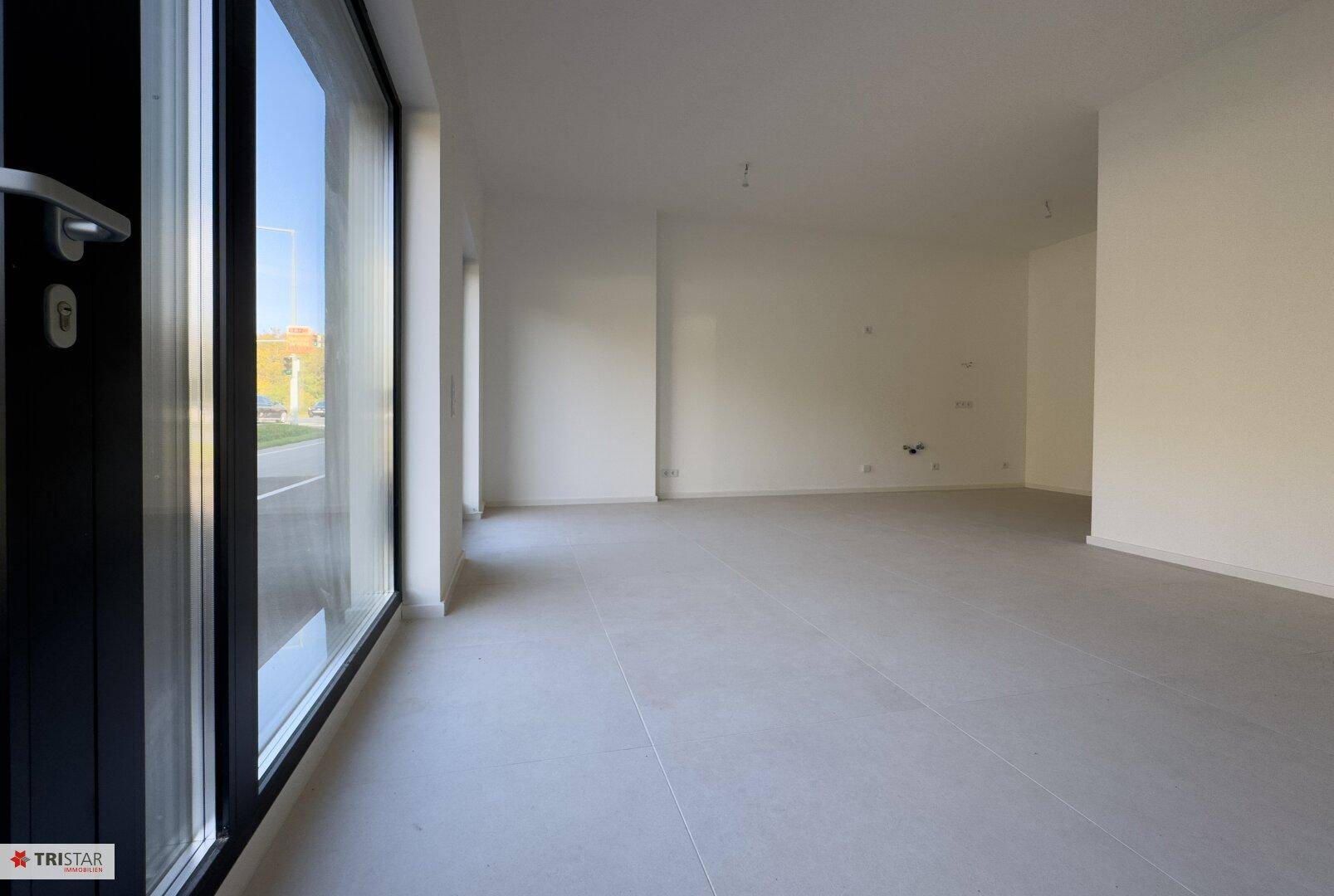 Lichtdurchfluteter Raum mit großen Fenstern und Fliesenboden, bietet einen Blick nach draußen.