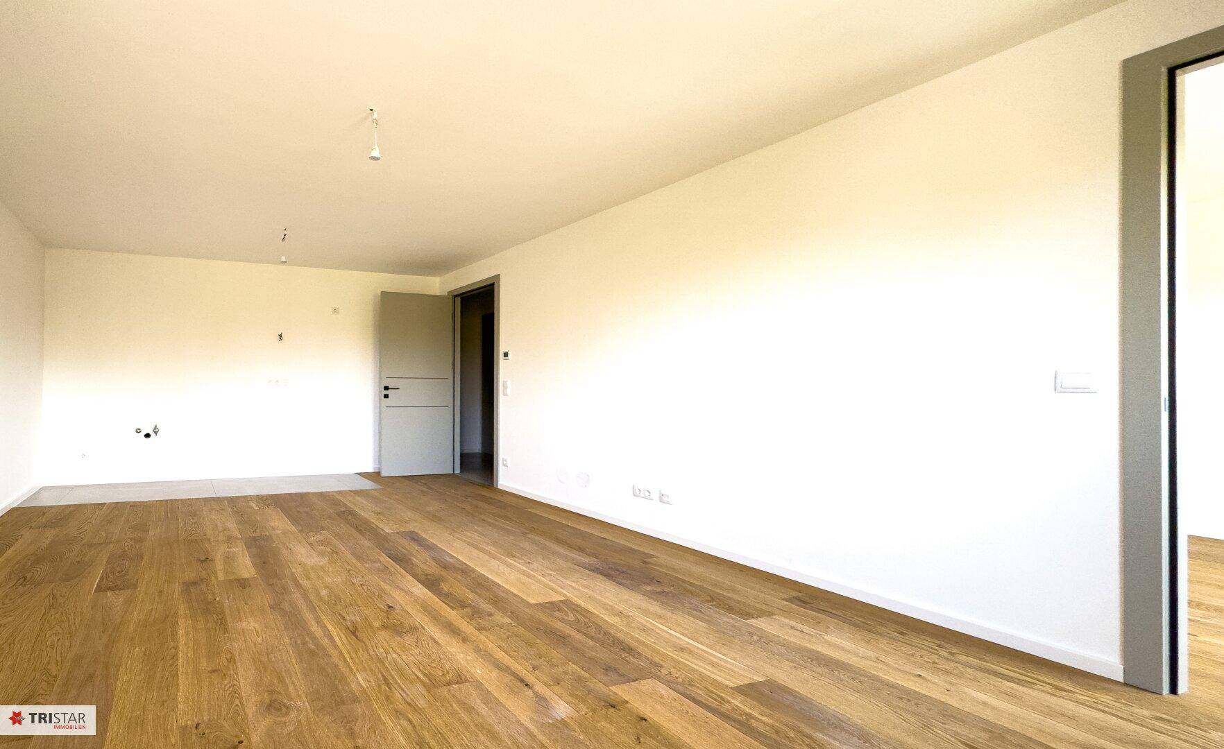 Leerer Raum mit Holzboden und weiß gestrichenen Wänden, bereit für die Einrichtung.