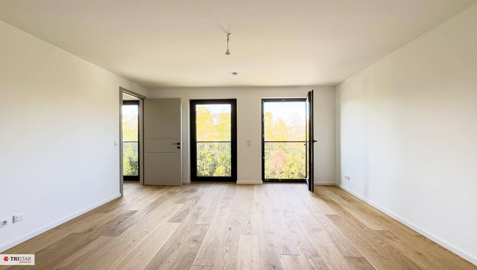 Geräumiges, helles Zimmer mit Holzboden und Zugang zu französischen Balkonen.