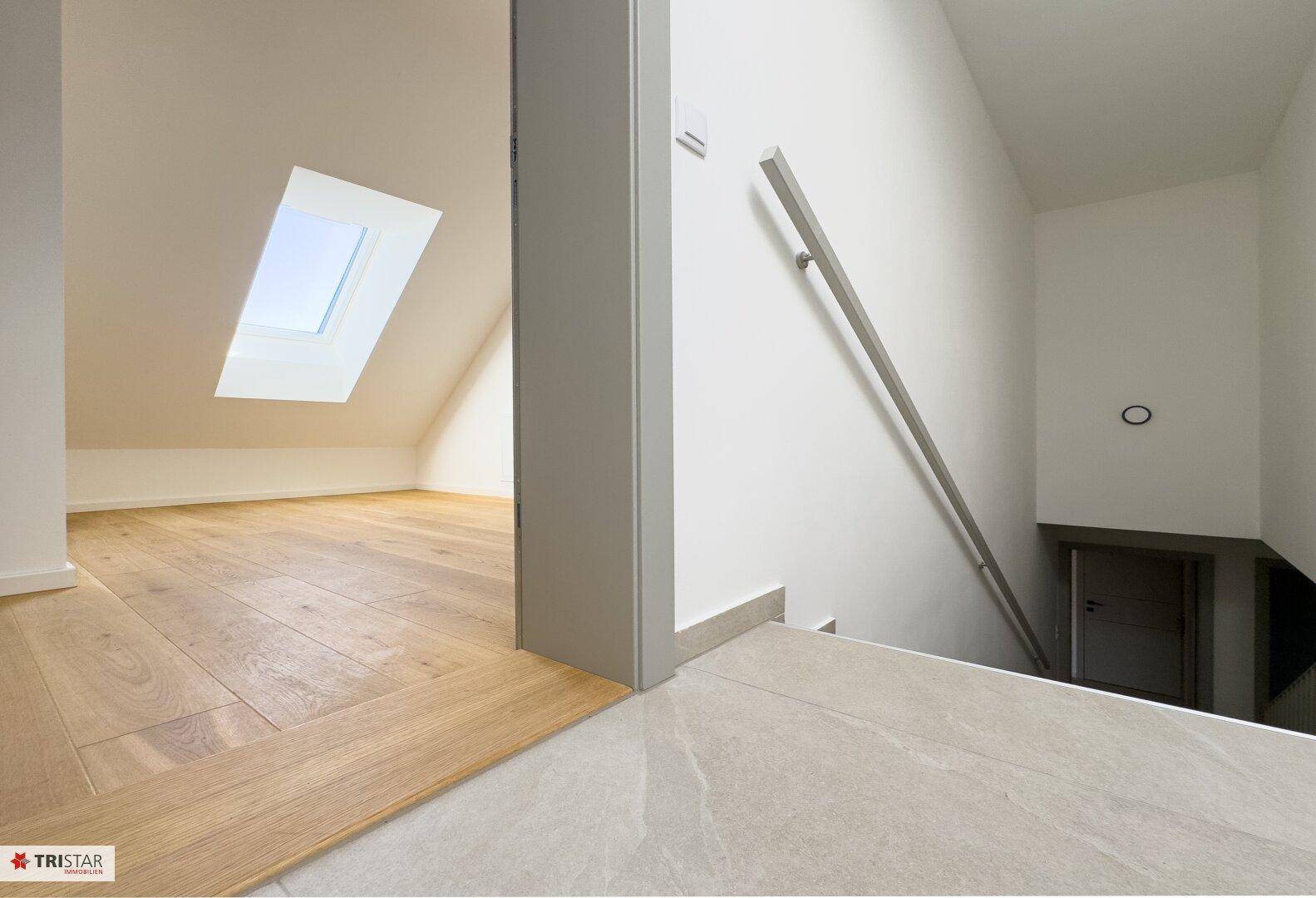 Heller Treppenbereich mit Fliesenboden und einem Dachfenster, das den Raum mit Licht durchflutet.