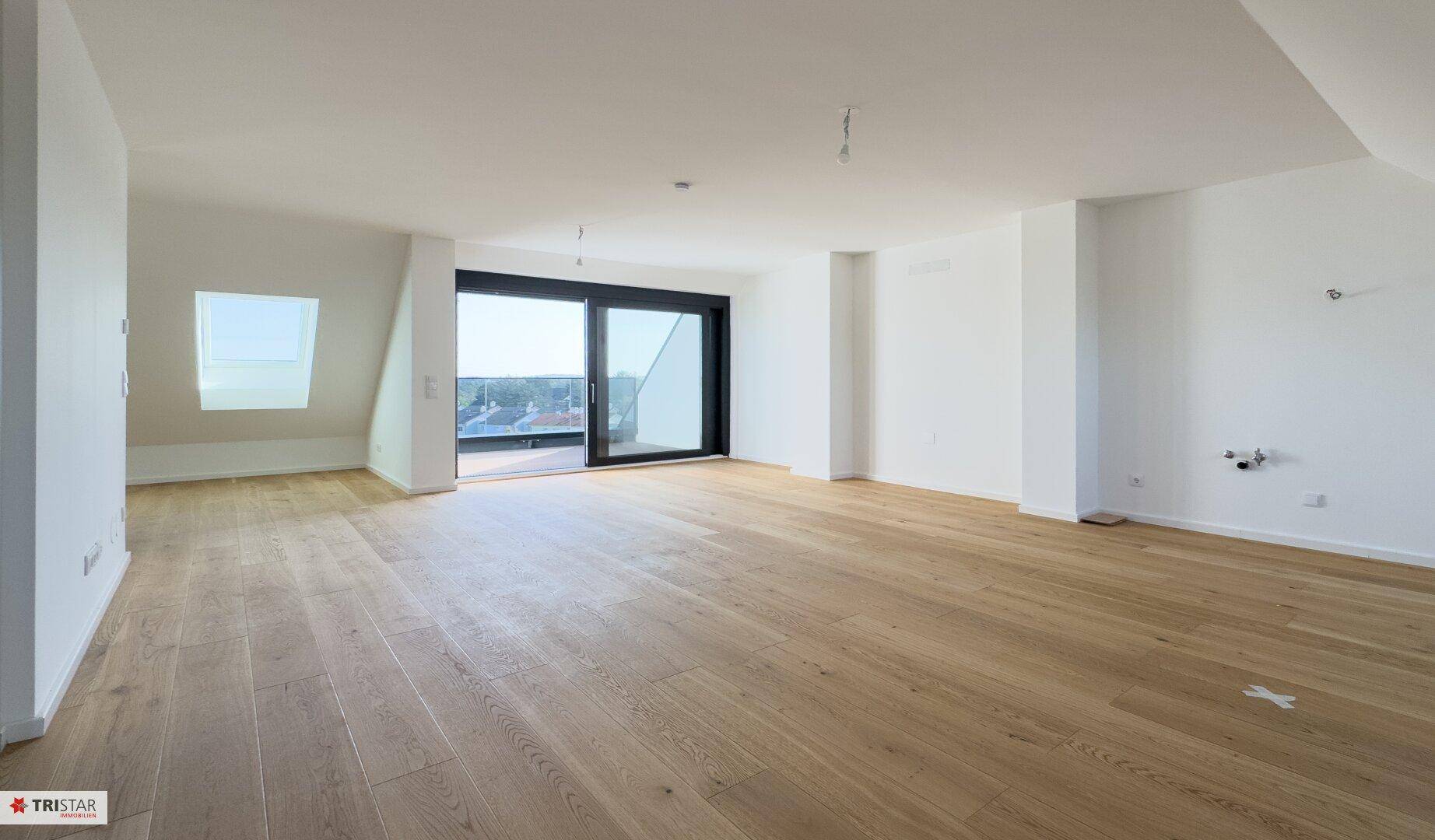 Heller und geräumiger Wohnbereich mit Holzboden und Zugang zur Terrasse, ideal für offenes Wohnen.