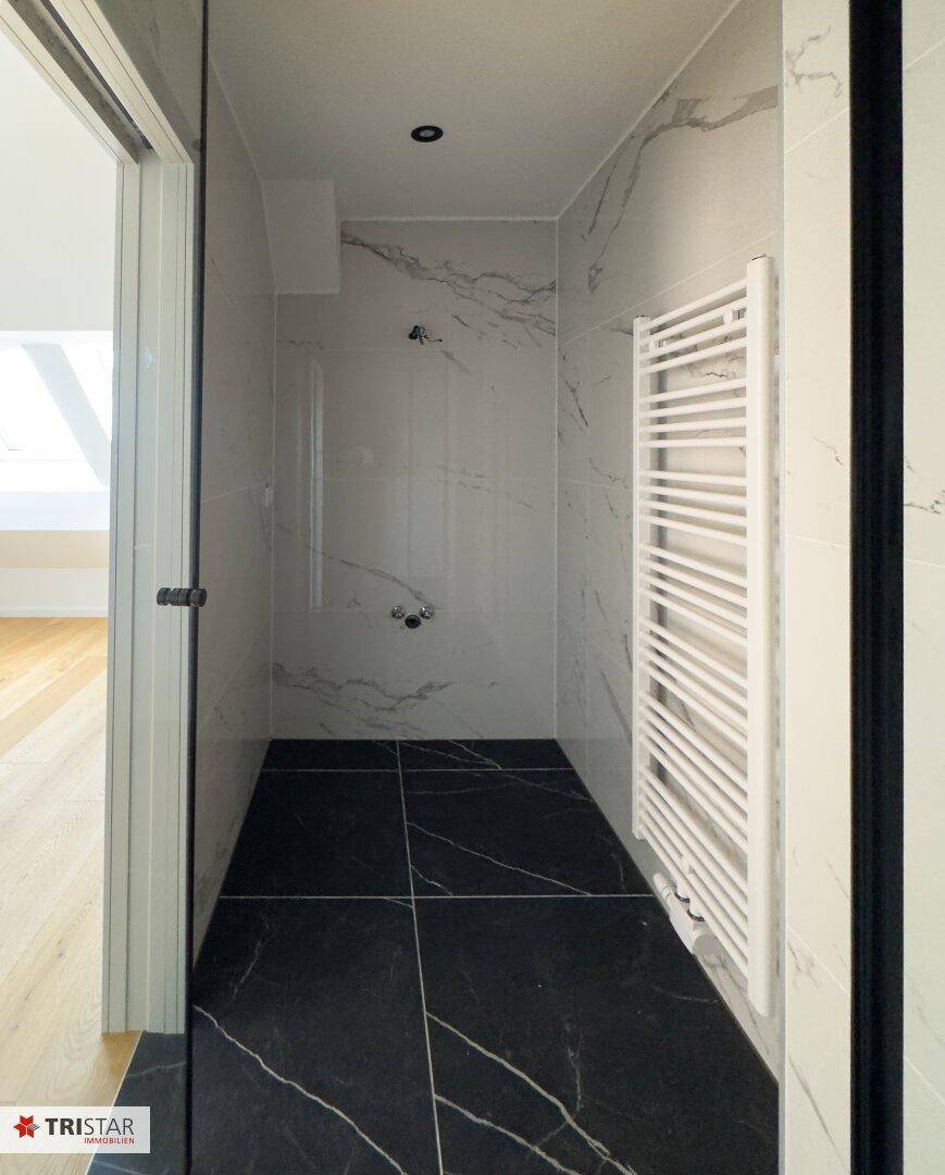 Modernes Badezimmer mit eleganten Marmorfliesen und einer ebenerdigen Dusche.