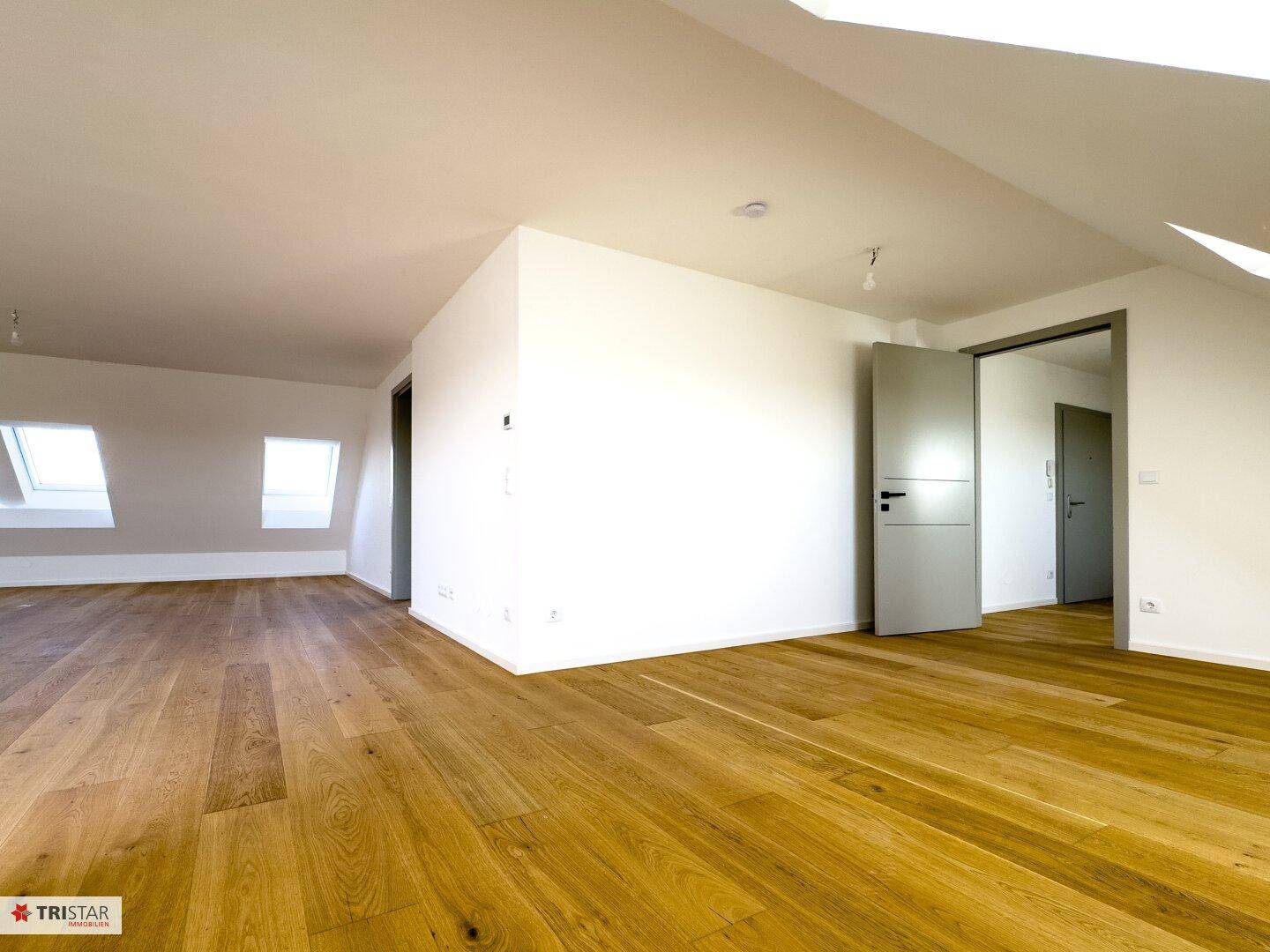 Geräumiger Wohnbereich mit hellem Holzboden und modernen Türen, die zu weiteren Räumen führen.