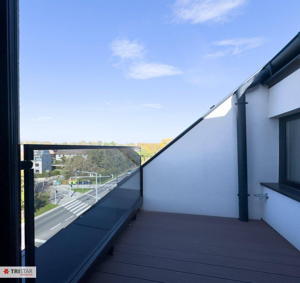 Moderne Terrasse mit Glasgeländer und weitem Blick über die Stadt und die Landschaft.