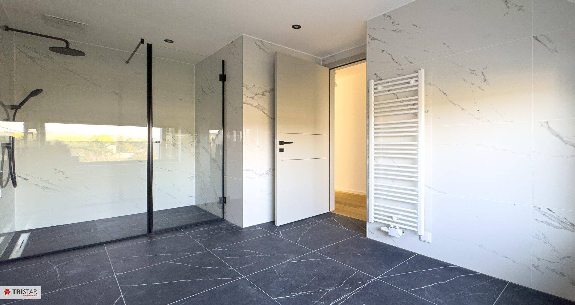 Großes, modernes Badezimmer mit Marmorfliesen, ebenerdiger Dusche und einem Fenster für Tageslicht.