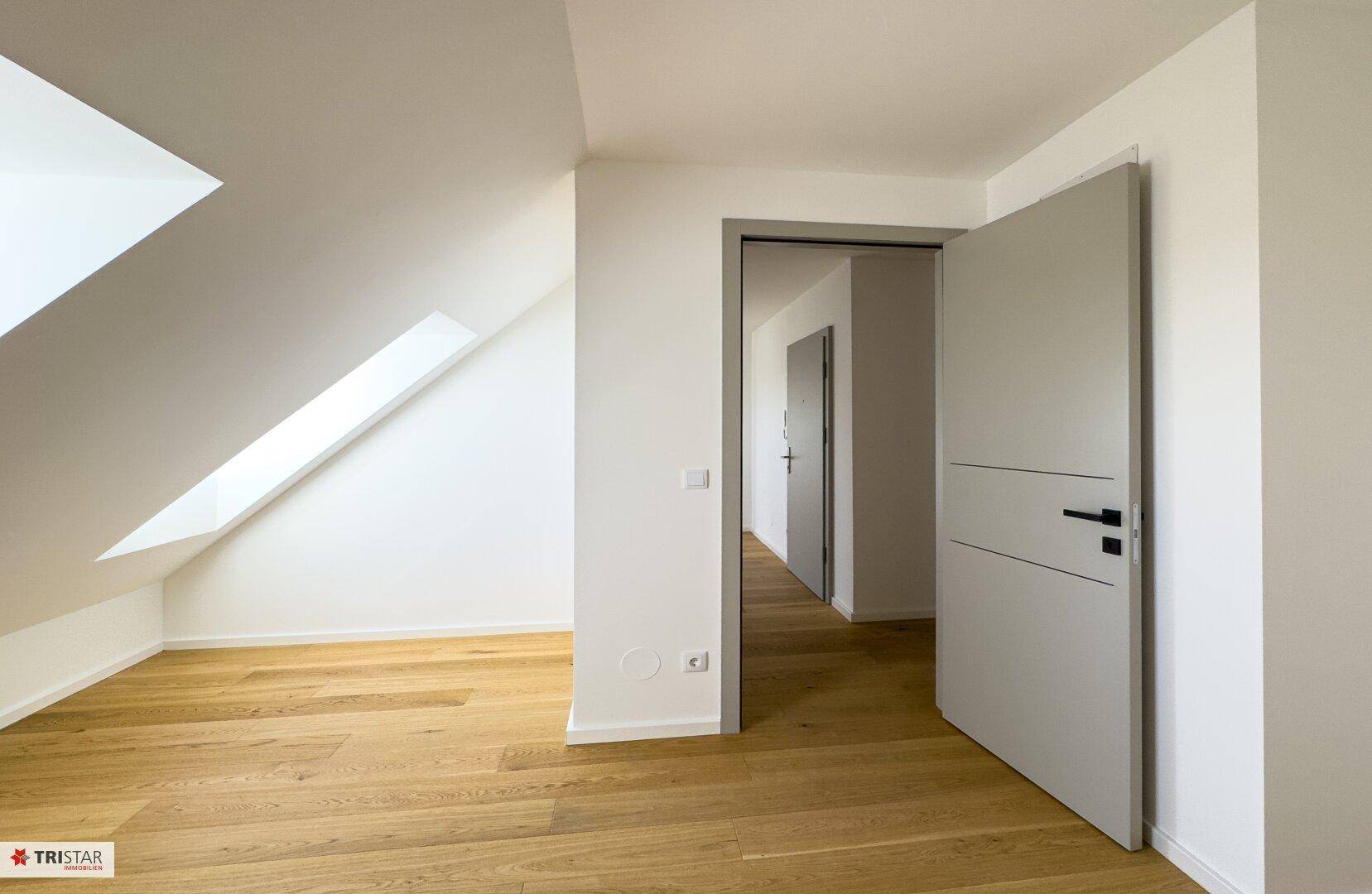 Helles Zimmer mit Holzboden und Dachfenstern, ideal als Schlafzimmer oder Arbeitszimmer.