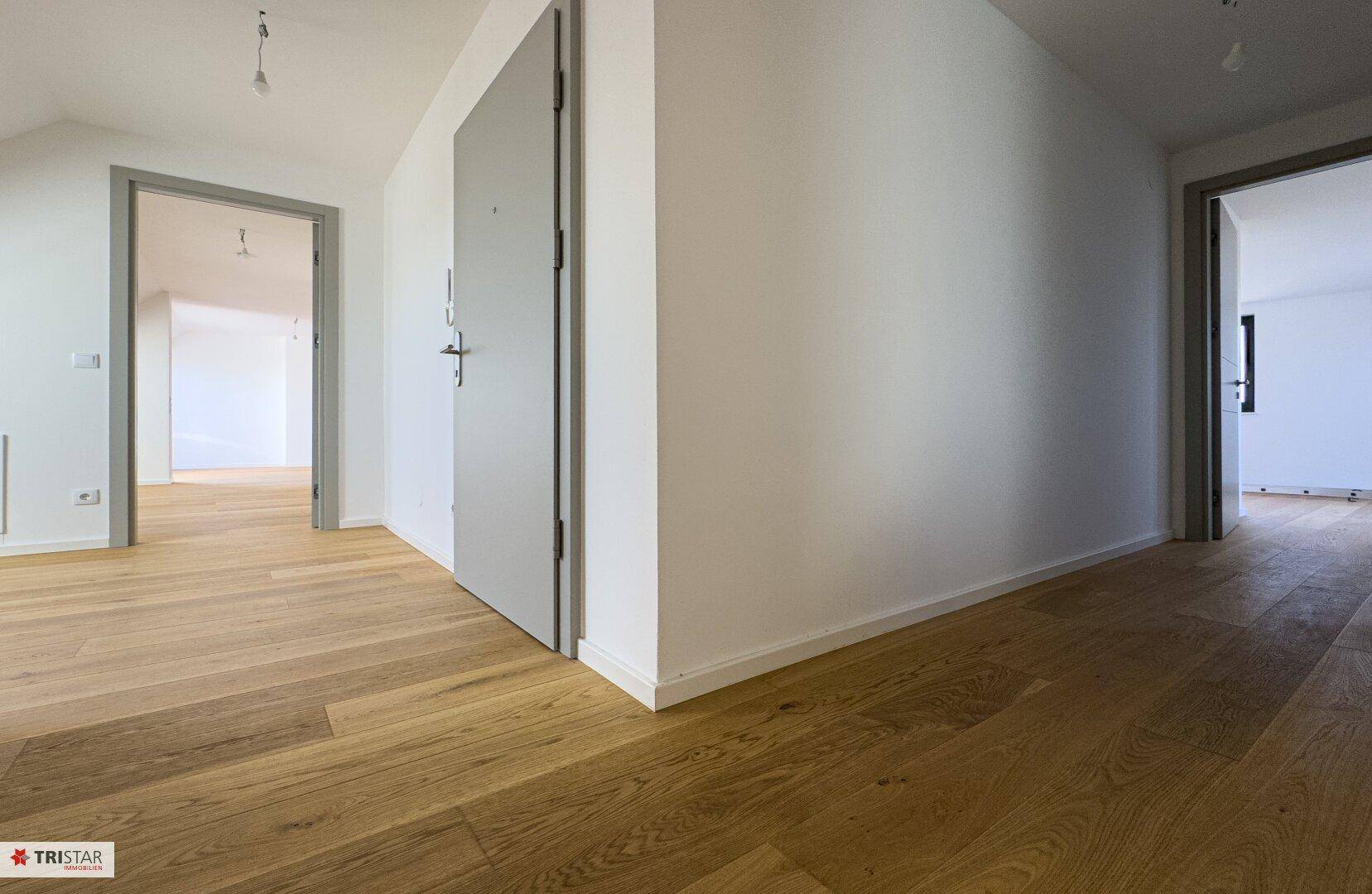 Heller Flur mit Holzboden und modernen Türen, die zu verschiedenen Räumen führen.