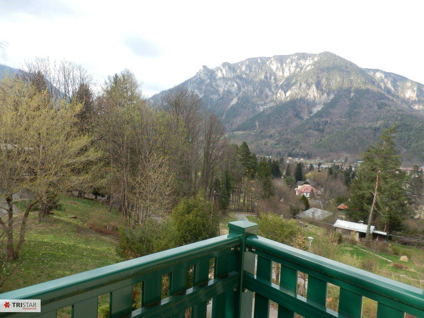 Kleiner Balkon mit grüner Brüstung und weitem Blick auf die Berge und die Umgebung.