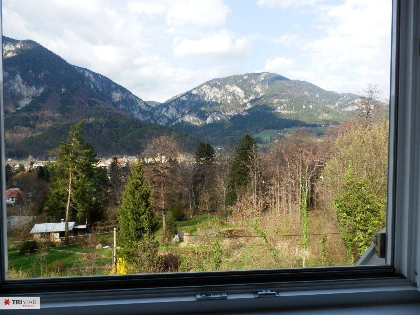 Panoramablick aus dem Fenster auf die umliegende Berglandschaft und grüne Natur.