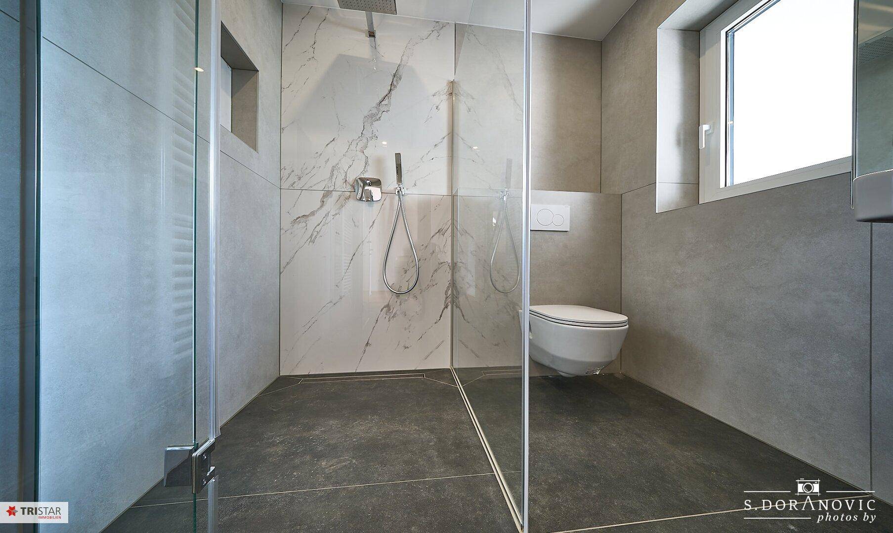 Detailansicht der begehbaren Dusche und des wandhängenden WCs im modernen Badezimmer.