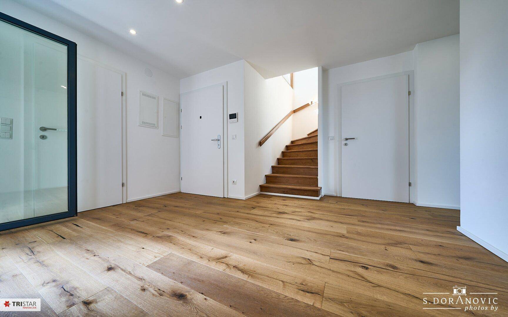 Geräumiger Eingangsbereich mit Holzboden und Holztreppe, verbindet die verschiedenen Räume.