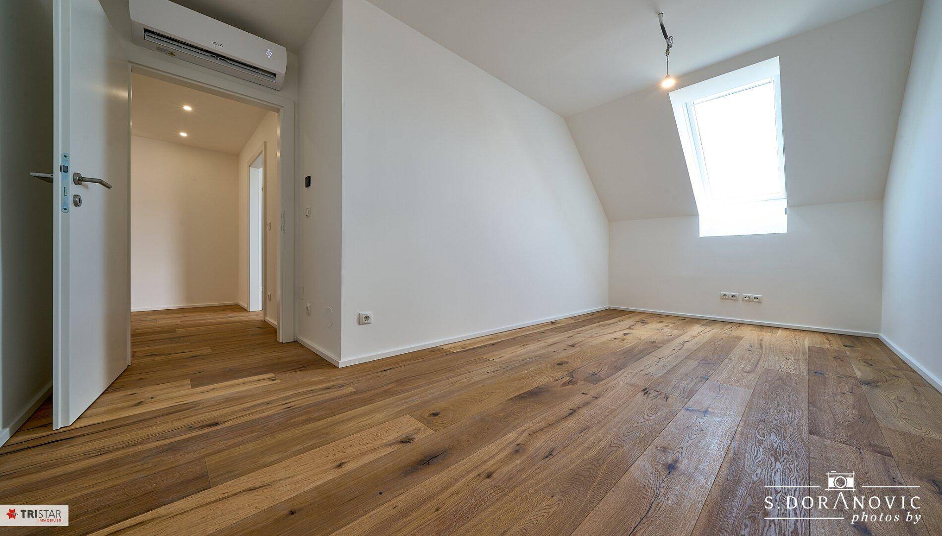 Geräumiges Dachzimmer mit Holzboden, Oberlicht und Klimaanlage, bereit zum Einrichten.