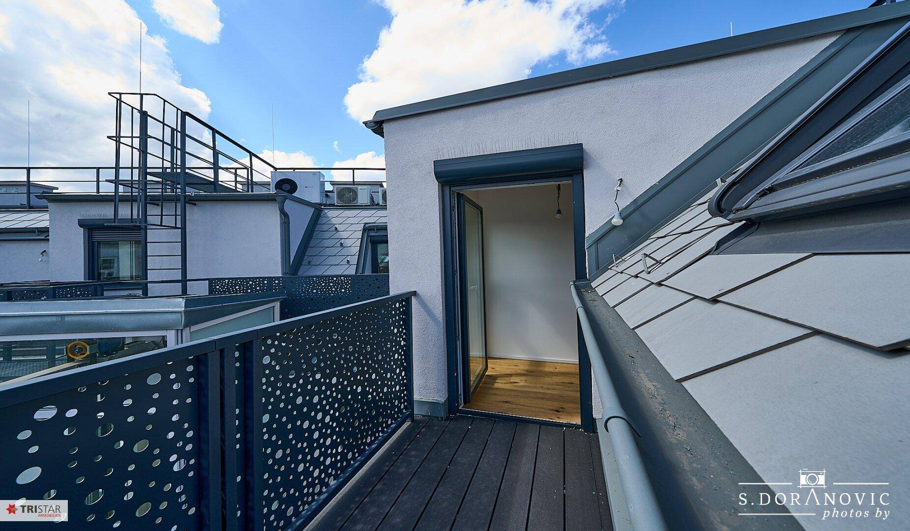 Moderner Balkon mit perforiertem Metallgeländer und Holzboden, bietet einen schönen Ausblick.