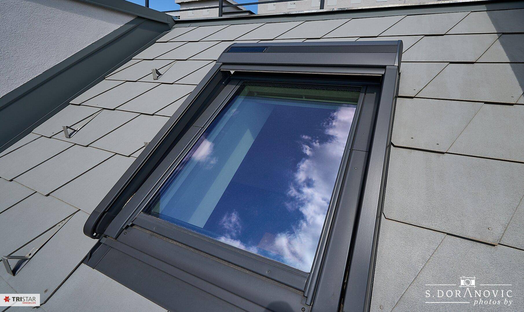 Dachfenster mit Rollladen auf einem Ziegeldach, bietet Schutz und Verdunkelung.