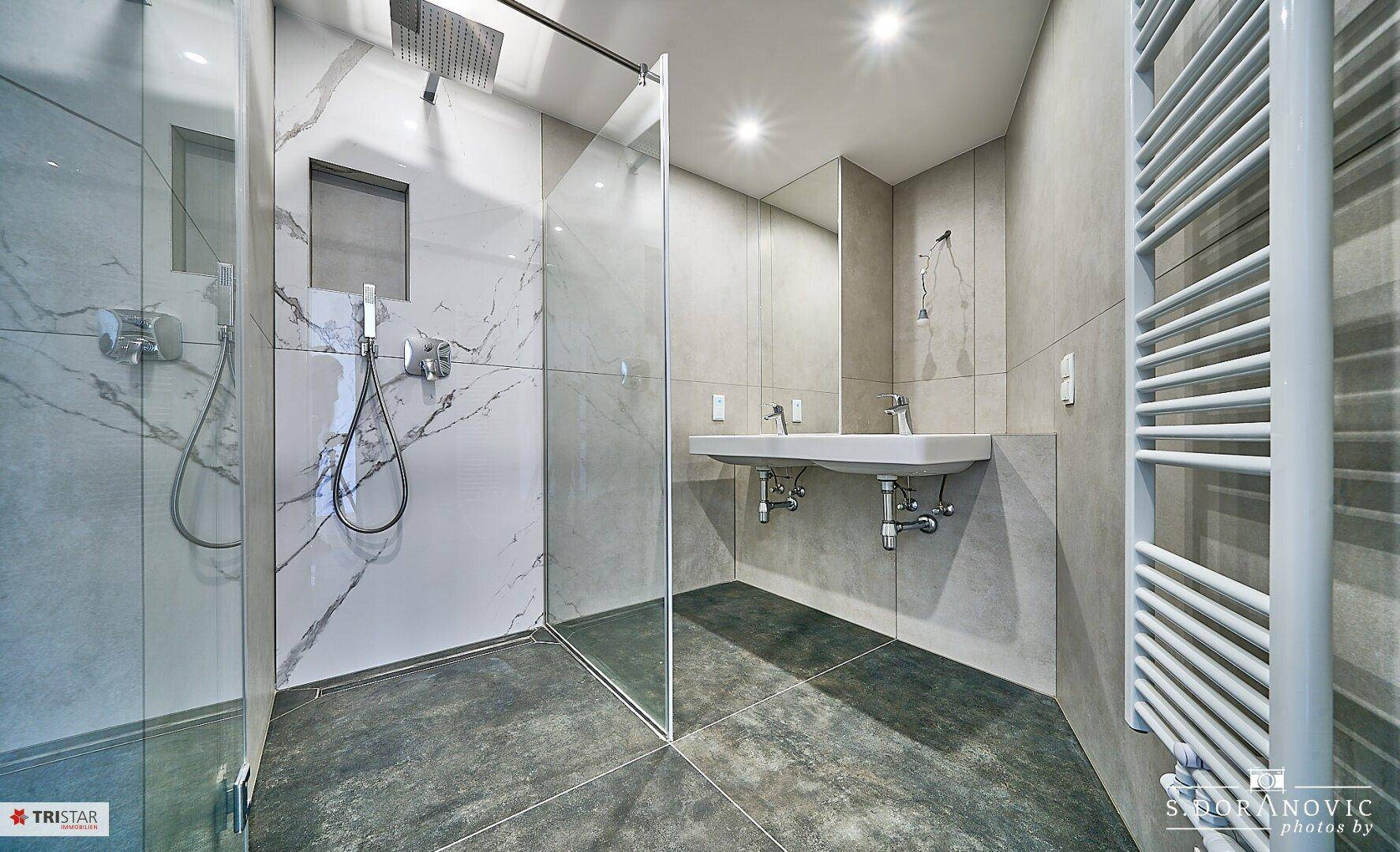 Modernes Badezimmer mit begehbarer Dusche, Doppelwaschbecken und beheiztem Handtuchhalter.