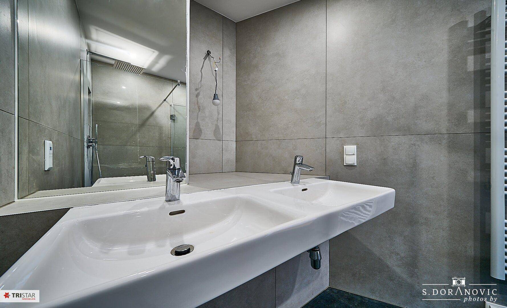 Doppelwaschbecken mit modernem Design und großem Spiegel, bietet Komfort und Funktionalität.
