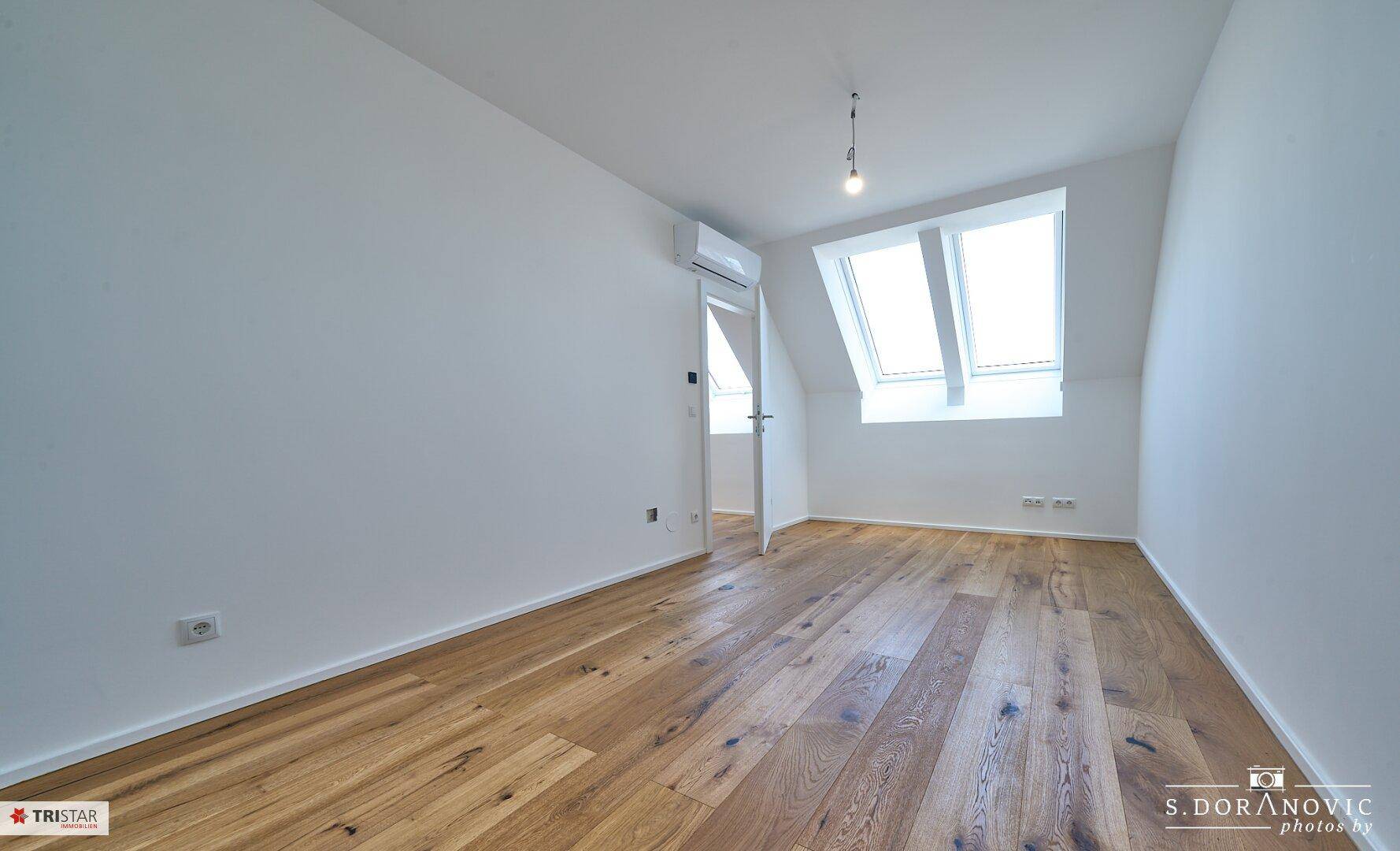 Schlafzimmer im Dachgeschoss mit Holzboden und Dachfenster, bietet eine helle und gemütliche Atmosphäre.