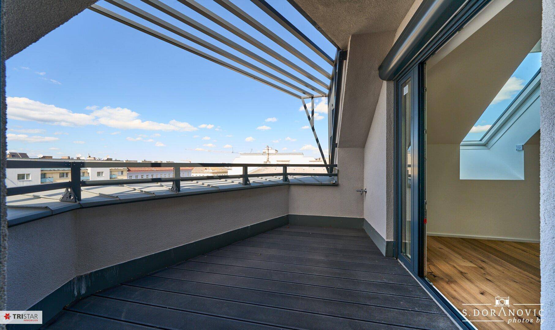 Moderner Balkon mit Holzboden und Stadtblick, ideal für Outdoor-Entspannung und frische Luft.