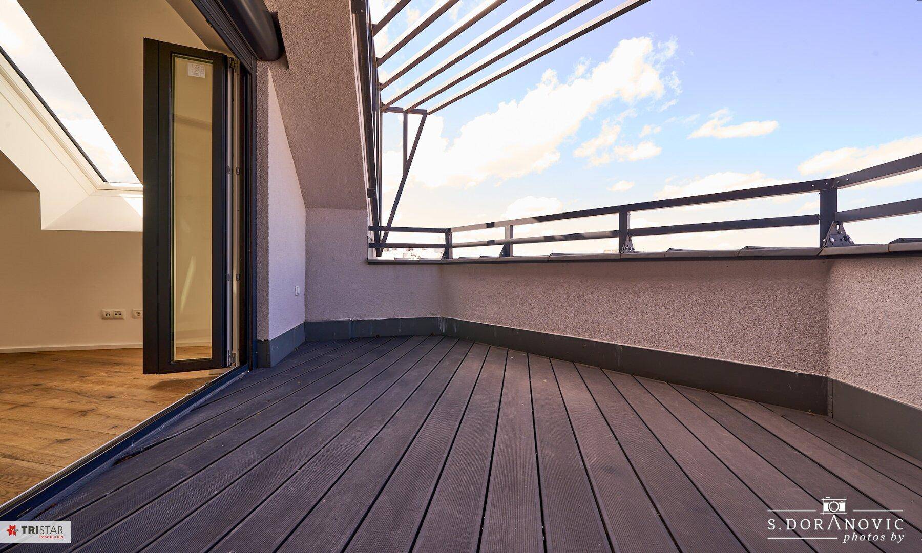 Geräumiger Balkon mit Holzboden und Metallgeländer, bietet Platz für entspannte Stunden im Freien.