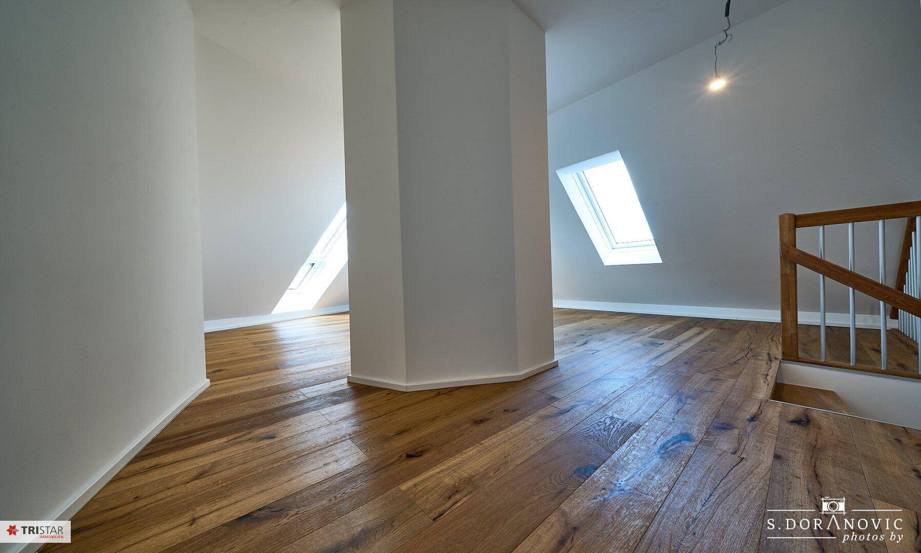 Offener Wohnbereich mit Holzboden und Treppe, verbindet die Ebenen und schafft ein großzügiges Raumgefühl.