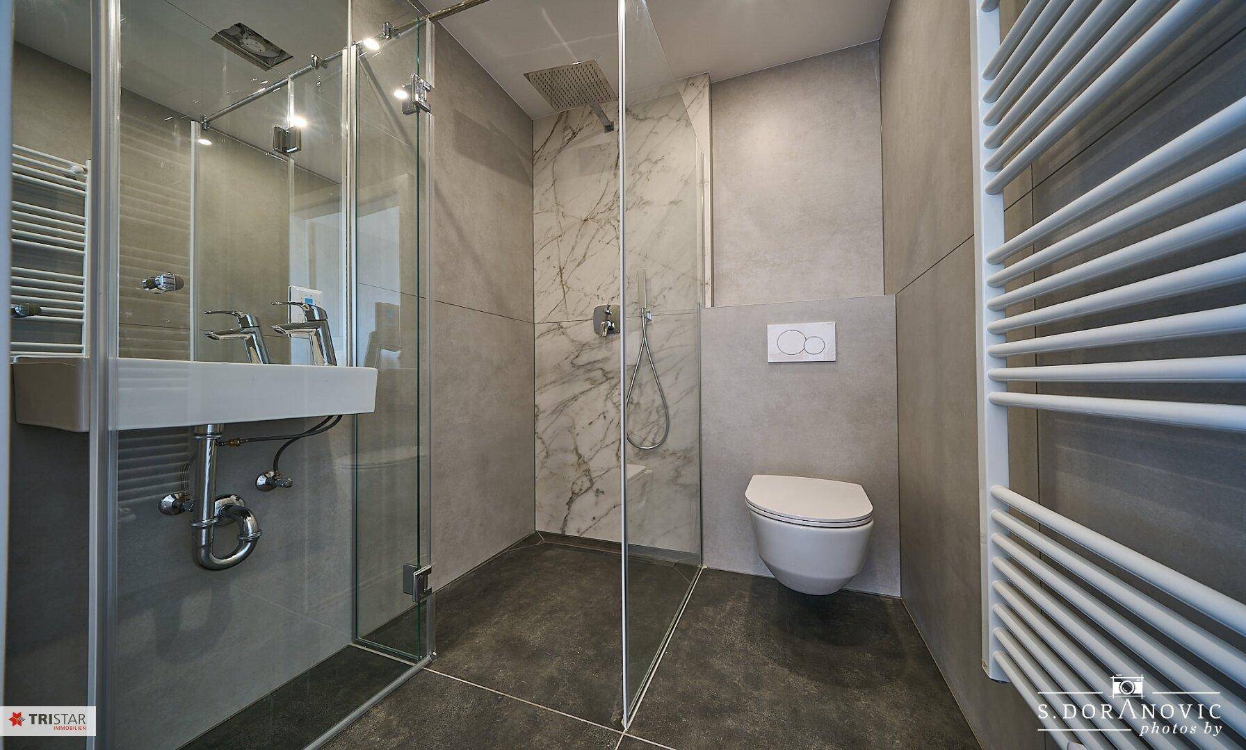 Elegantes Badezimmer mit begehbarer Dusche, wandhängendem WC und beheiztem Handtuchhalter.