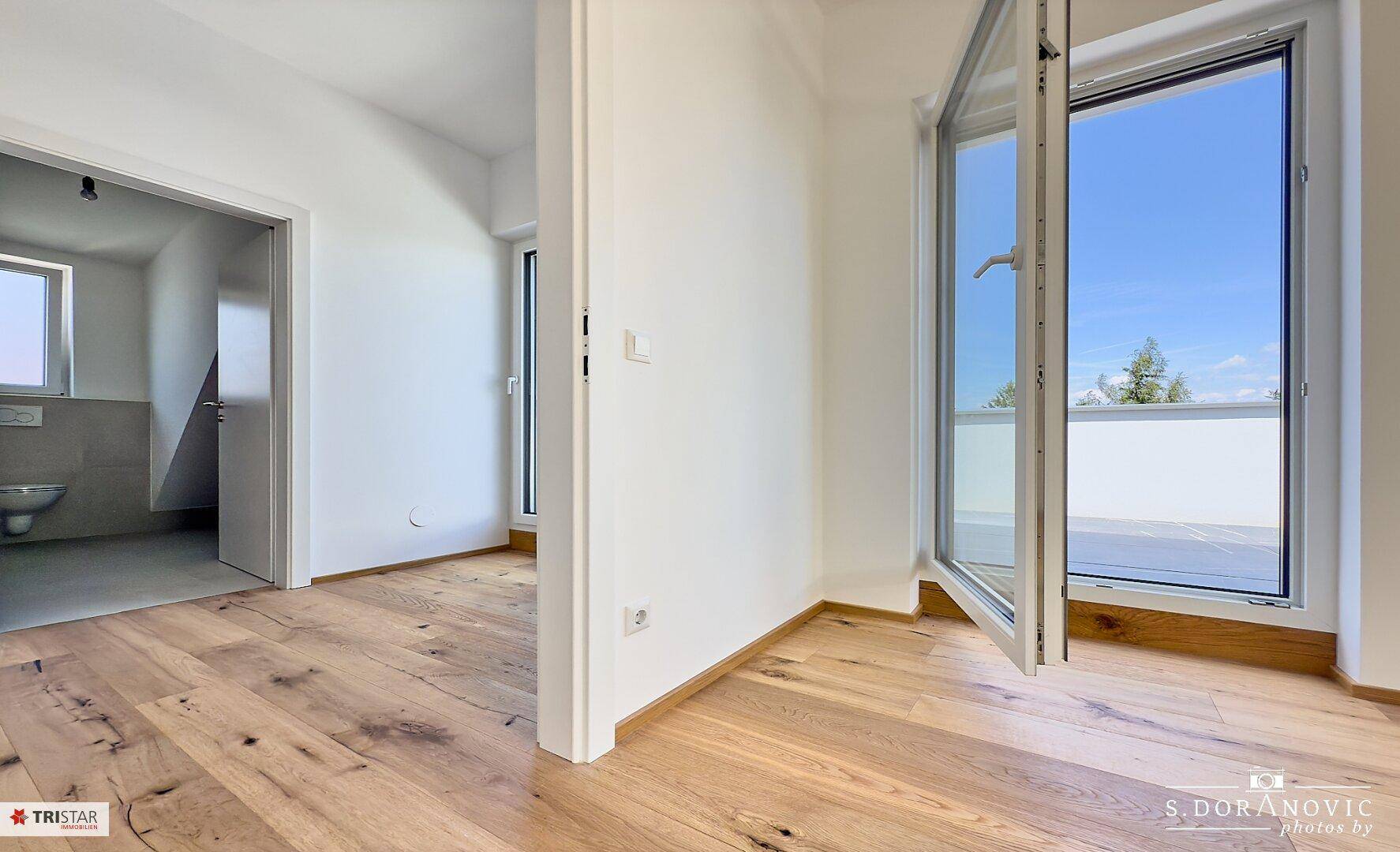 Helles Zimmer mit Holzboden und Zugang zu einem Außenbereich, ideal als Schlafzimmer nutzbar.