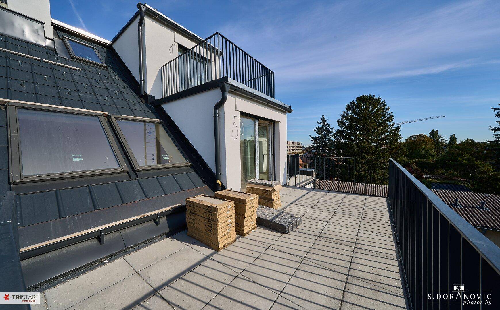 Geräumige Dachterrasse mit Fliesenboden und Blick auf die Umgebung, ideal für Entspannung im Freien.