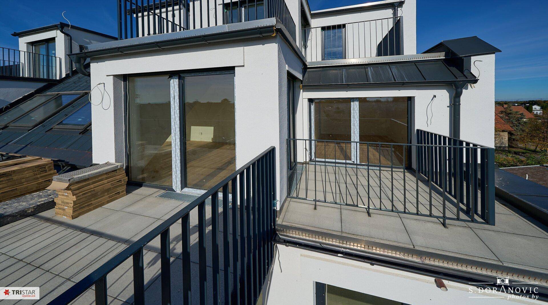 Mehrere Dachterrassenbereiche mit Fliesenboden und Metallgeländern, bieten sonnige Außenbereiche.