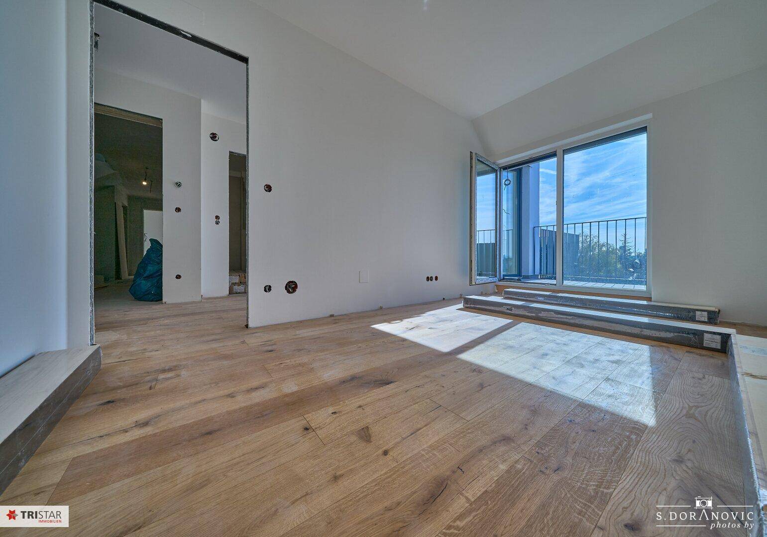 Unmöblierter Raum mit Holzboden und Zugang zu einem Balkon, ideal für individuelle Gestaltung.