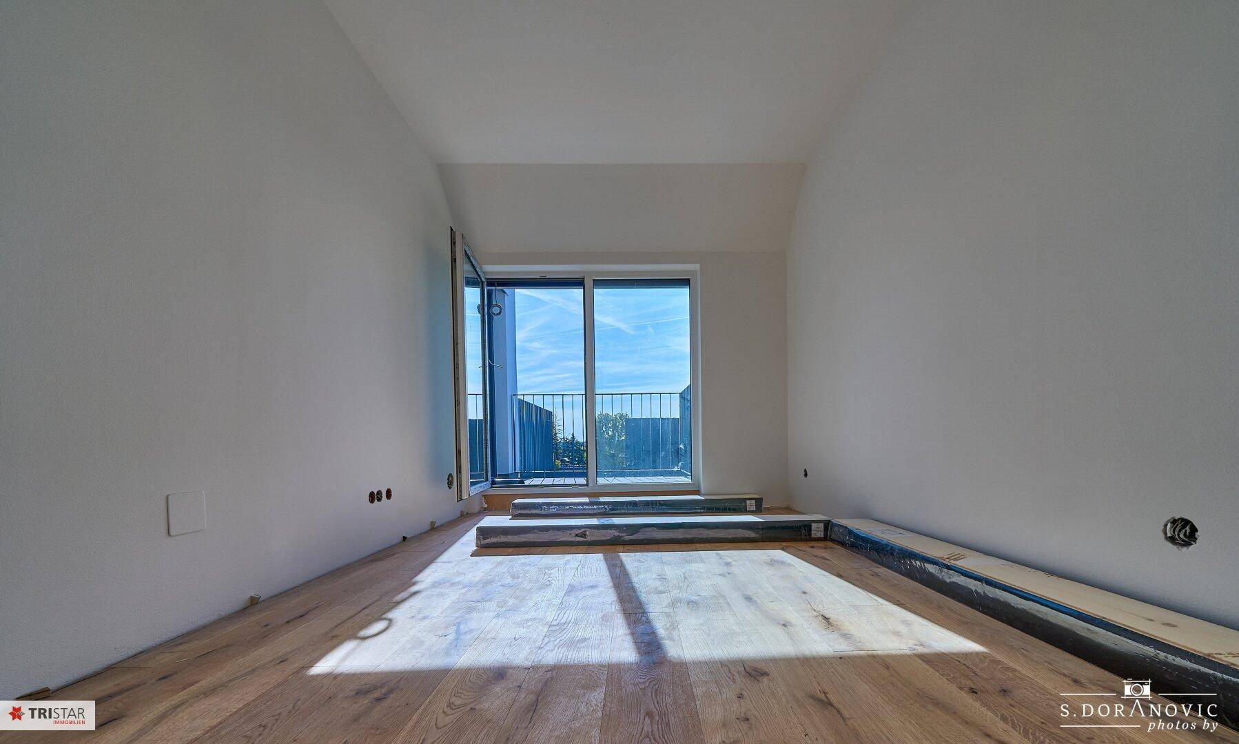 Unmöblierter Raum mit Holzboden und Zugang zu einem Balkon, ideal für individuelle Gestaltung.