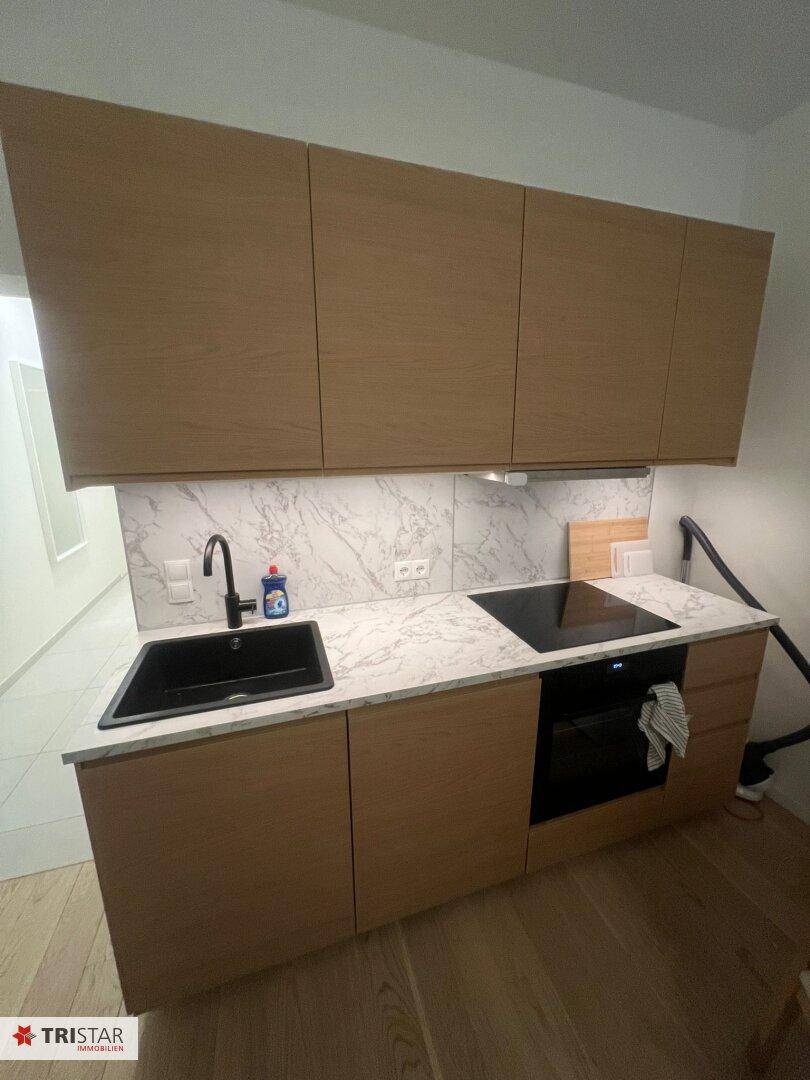 Moderne Küchenzeile mit Holzfronten, Marmor-Arbeitsplatte und integrierten Geräten.