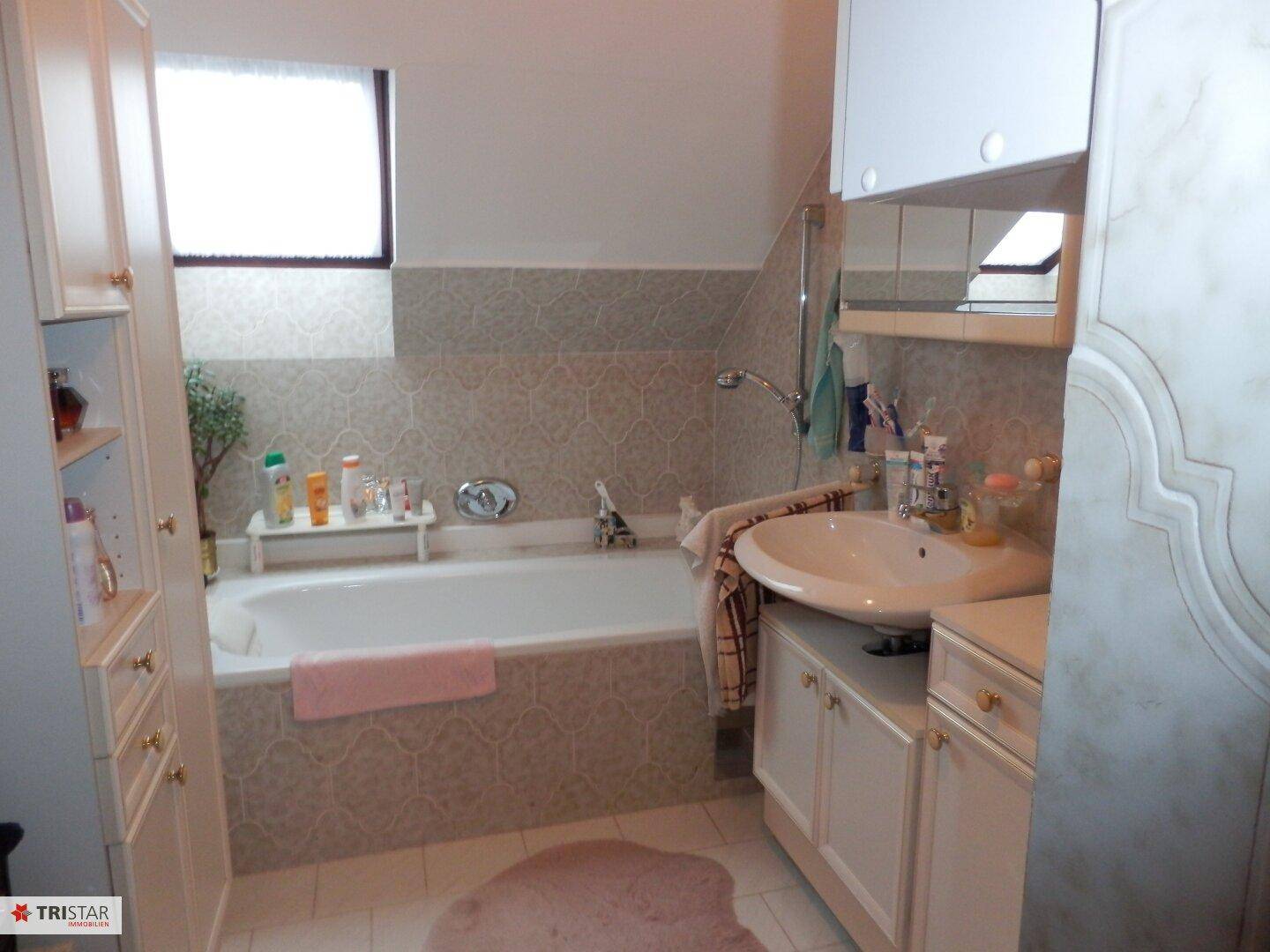 Badezimmer mit Badewanne, Waschbecken und Dachfenster in hellem Design.
