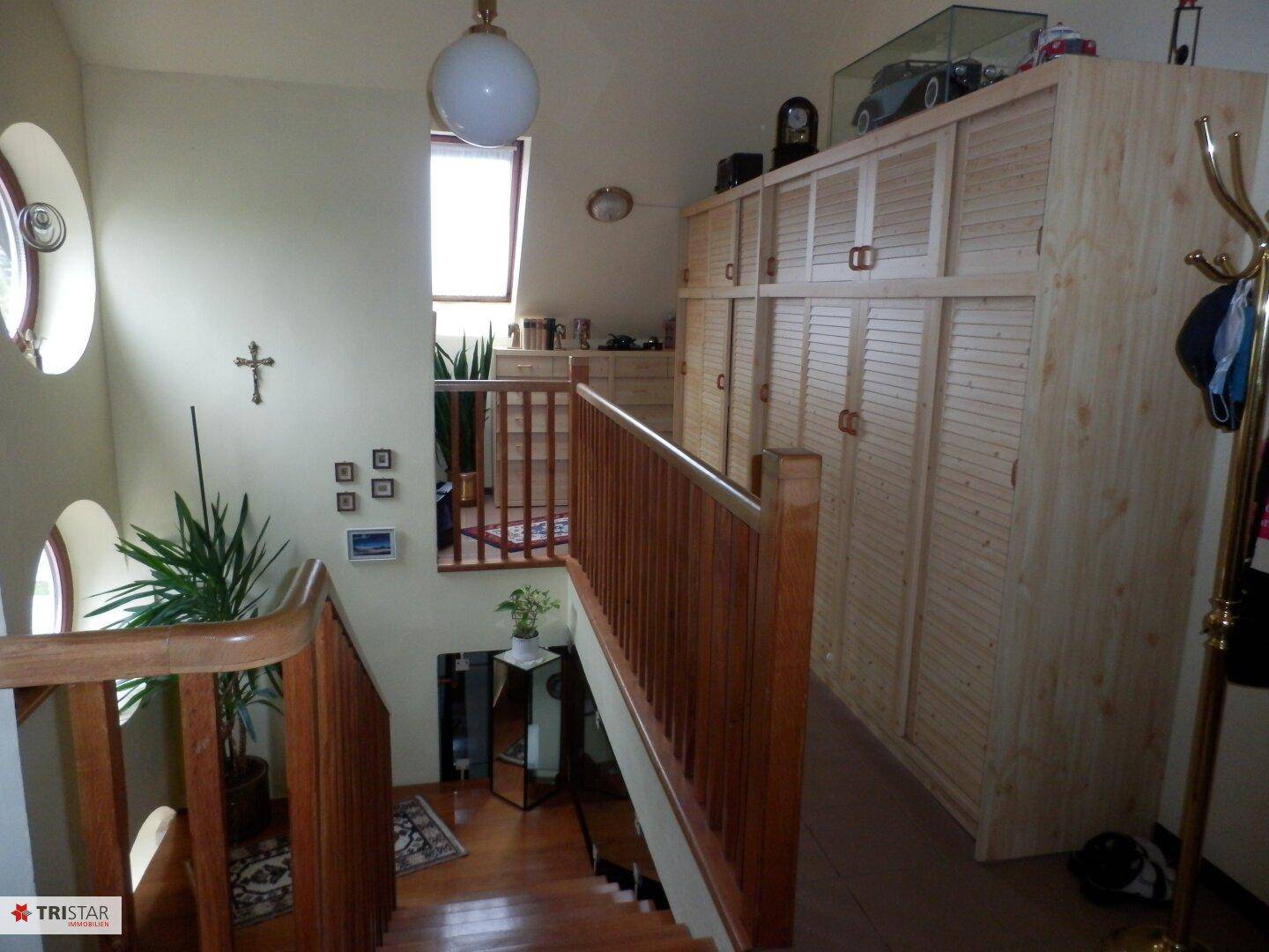 Heller Flur mit Holztreppe, Einbauschränken und Dachfenster.