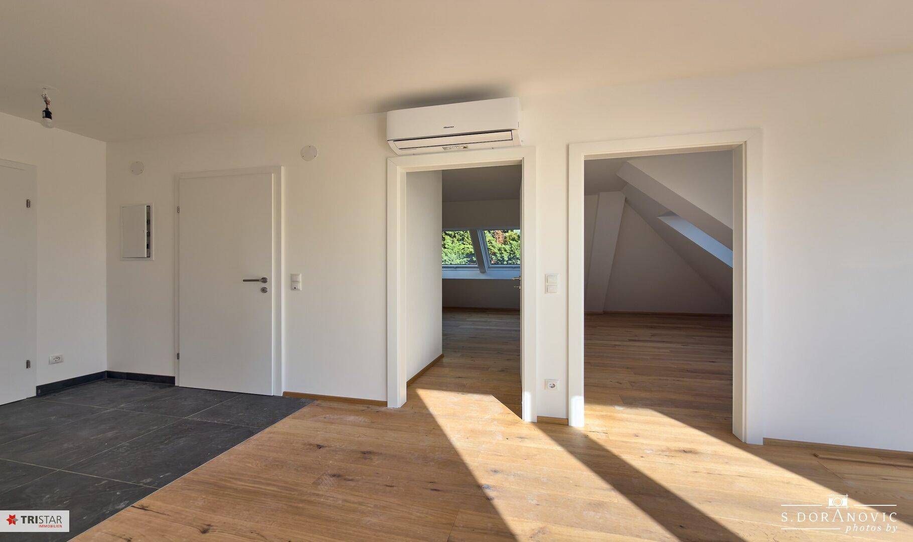 Heller Flur mit Holzboden und Zugang zu verschiedenen Räumen.