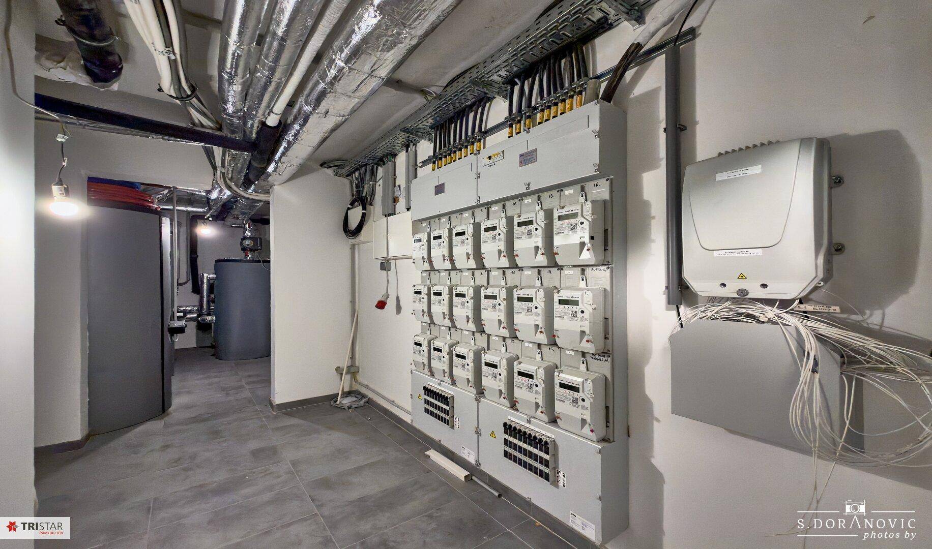 Technikraum im Keller mit vielen Zählern und sichtbaren Leitungen.
