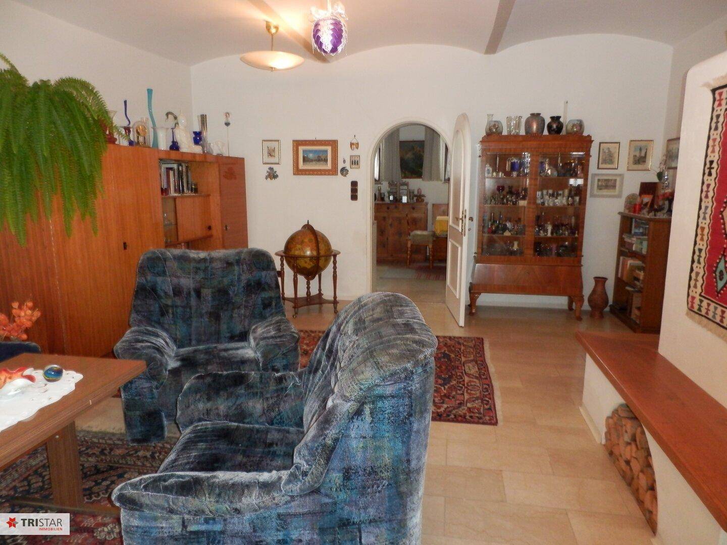 Gemütliches Wohnzimmer mit blauen Sesseln, Fliesenboden und traditioneller Einrichtung.