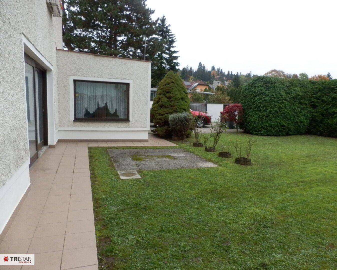 Großer Garten mit Rasenfläche und angrenzender Terrasse am Haus.